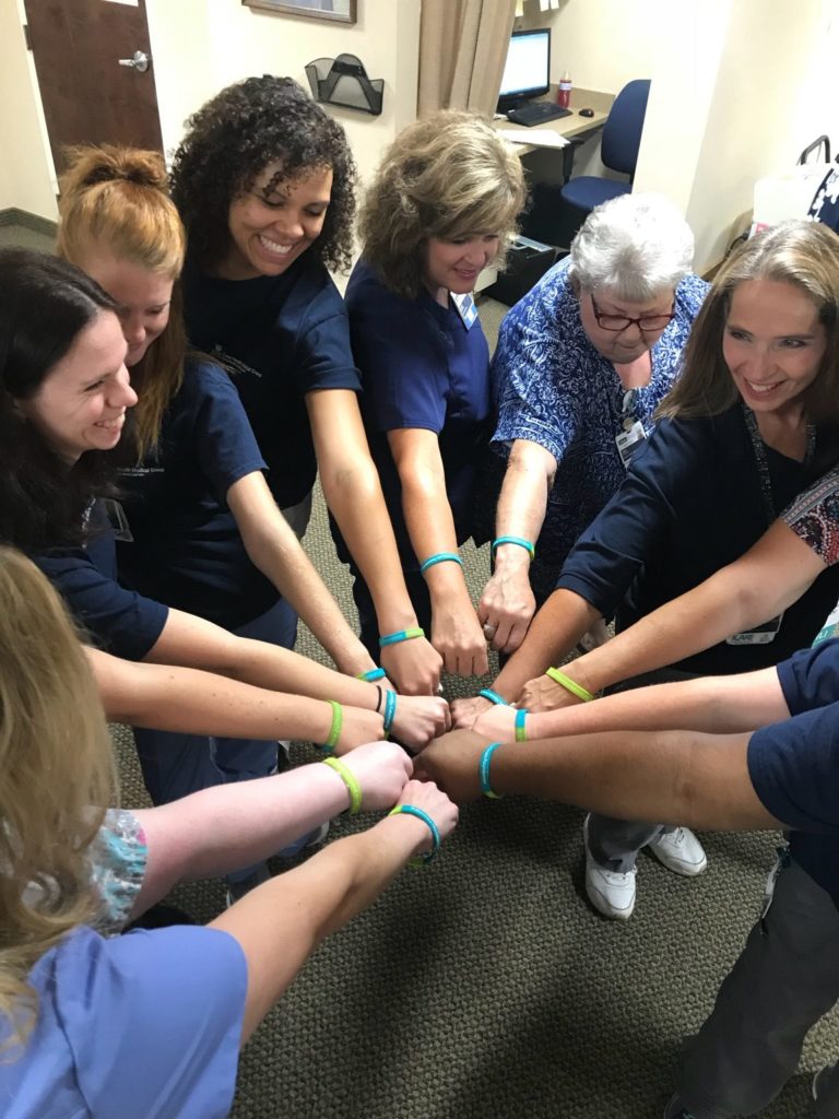 team holding wrists together in a circle