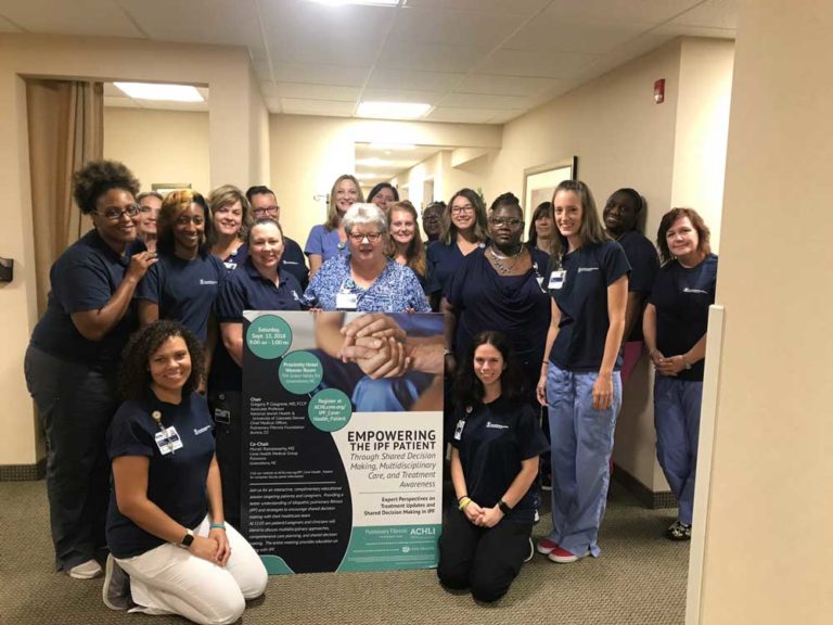 team gathered around sign